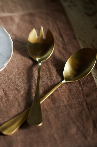 two salad spoons in gold on a wooden table