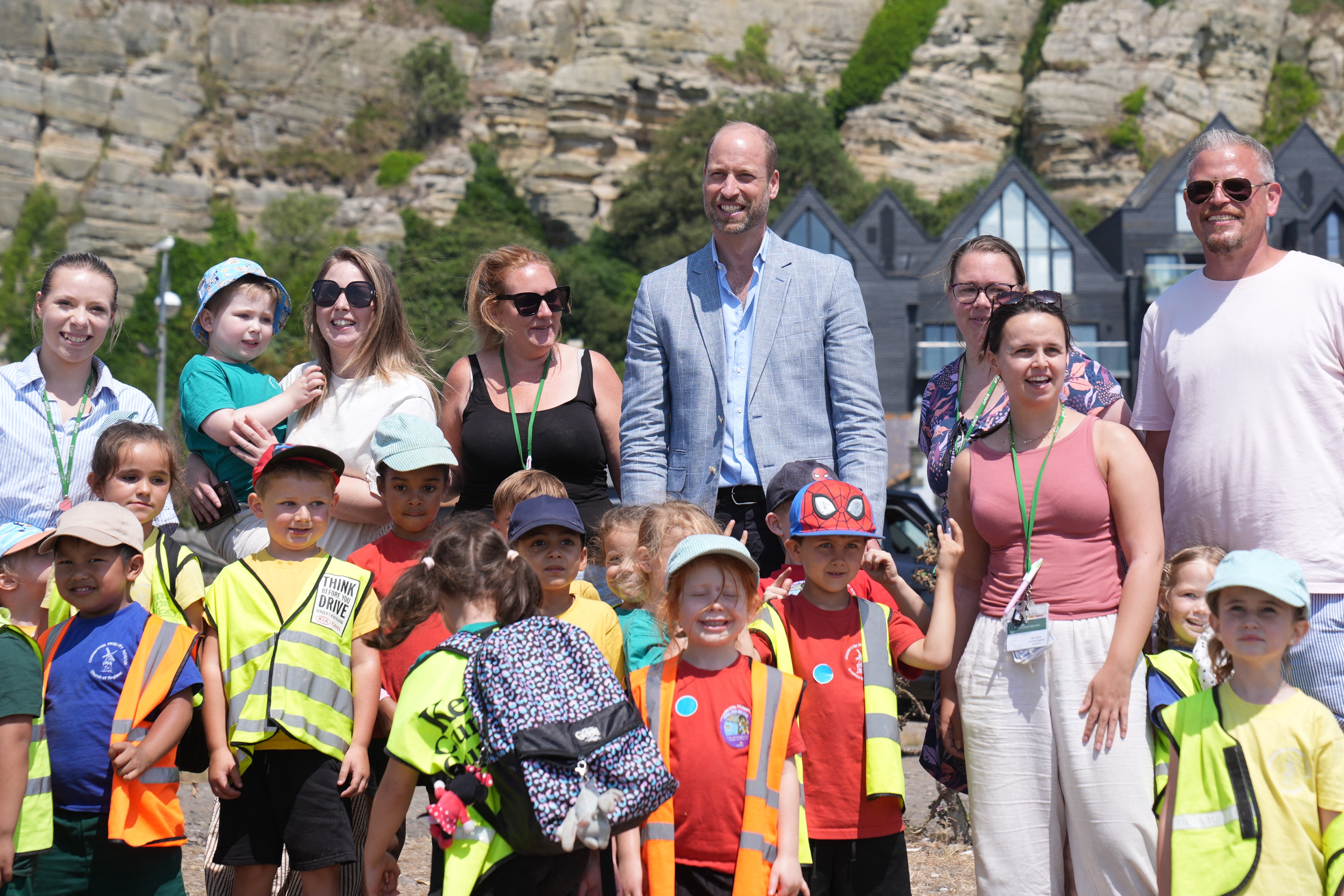Prince William wears a gray suit jacket, a blue shirt and black slacks to visit Hastings, where he meets children and royal fans on the seafront