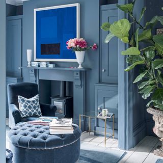 A dark blue living room with a tonal grey wood burner in a Victorian hearth fireplace