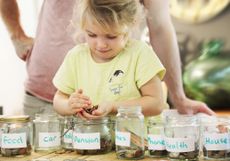 child putting money into savings jar