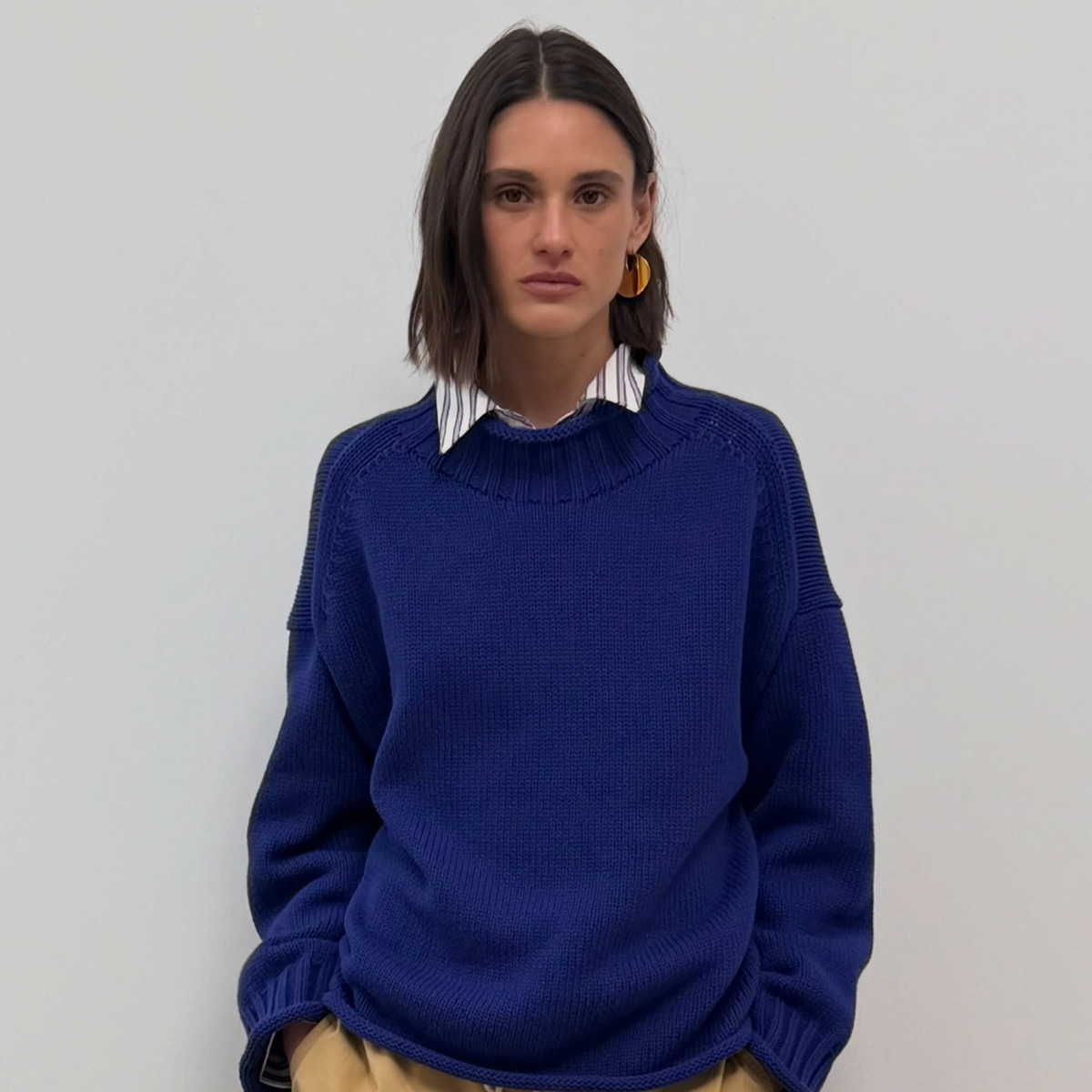 an image of a woman wearing a blue sweater with a stripe shirt underneath.