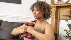 Woman in domestic setting holding dumbbells