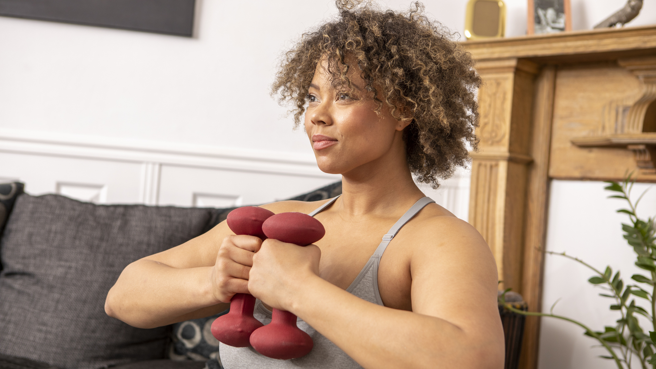 Woman in domestic setting holding dumbbells