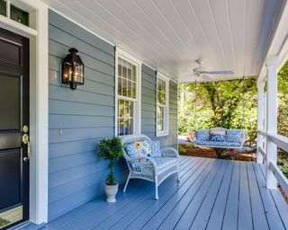 A porch with a painted deck and patio furniture
