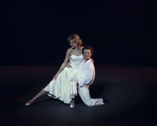 Emma Corrin wearing a white dress and recreating Princess Diana's dance with Wayne Sleep in The Crown