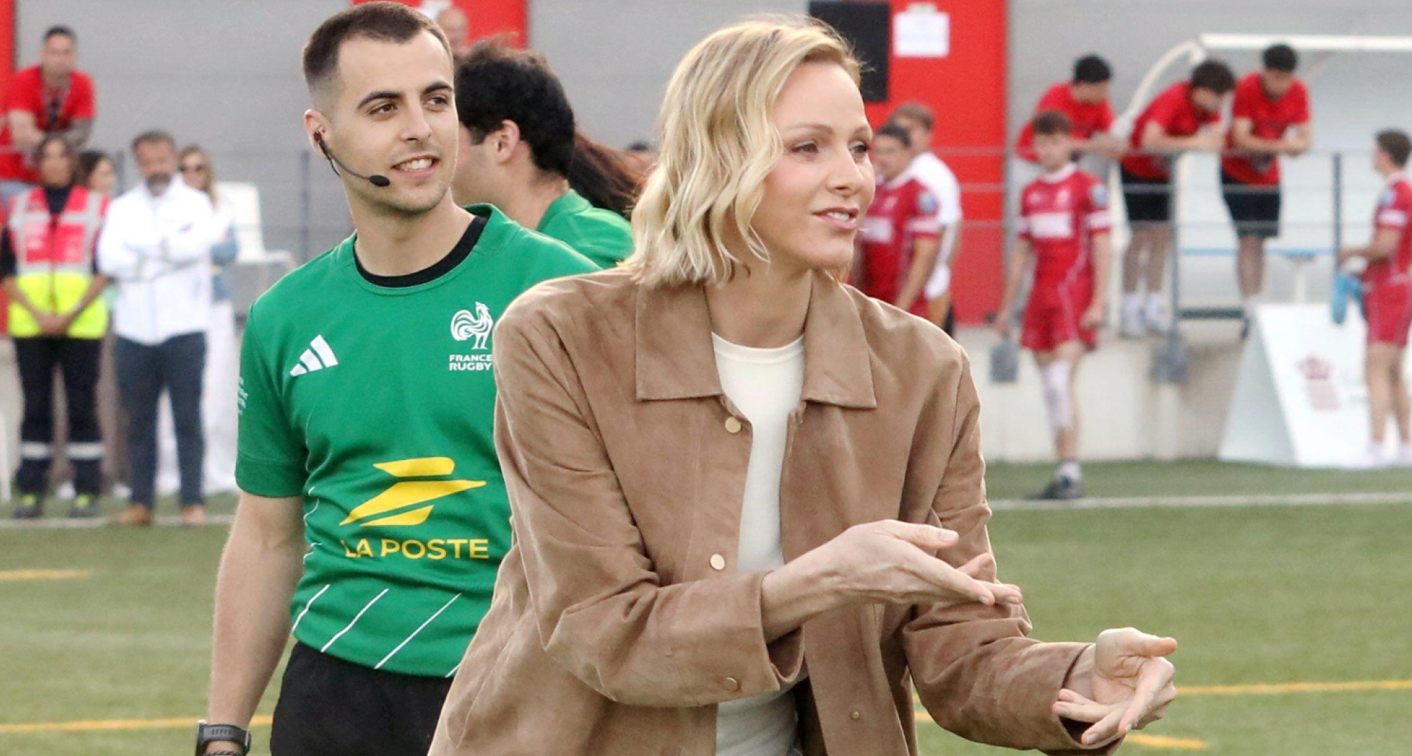 Princess Charlene wearing a brown jacket catching a ball