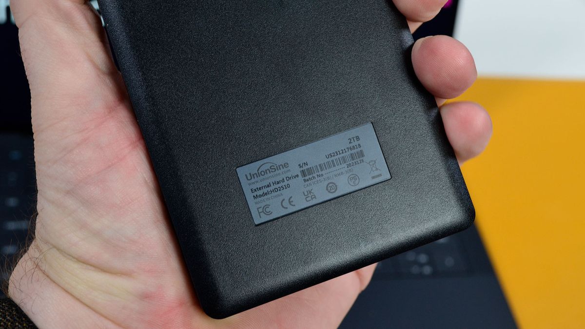 A masculine hand holding a UnionSine Ultra Slim external HDD