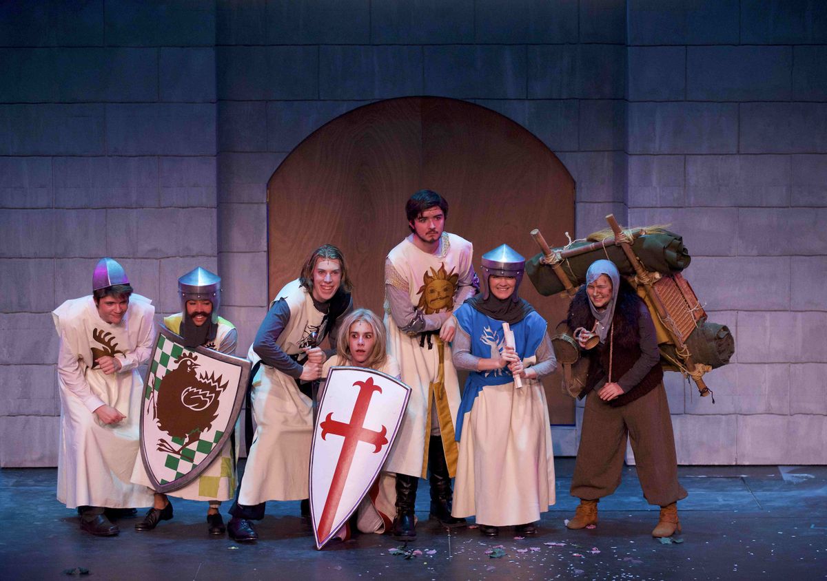 A group of actors are costumed in medieval garb, smiling for a group photo.