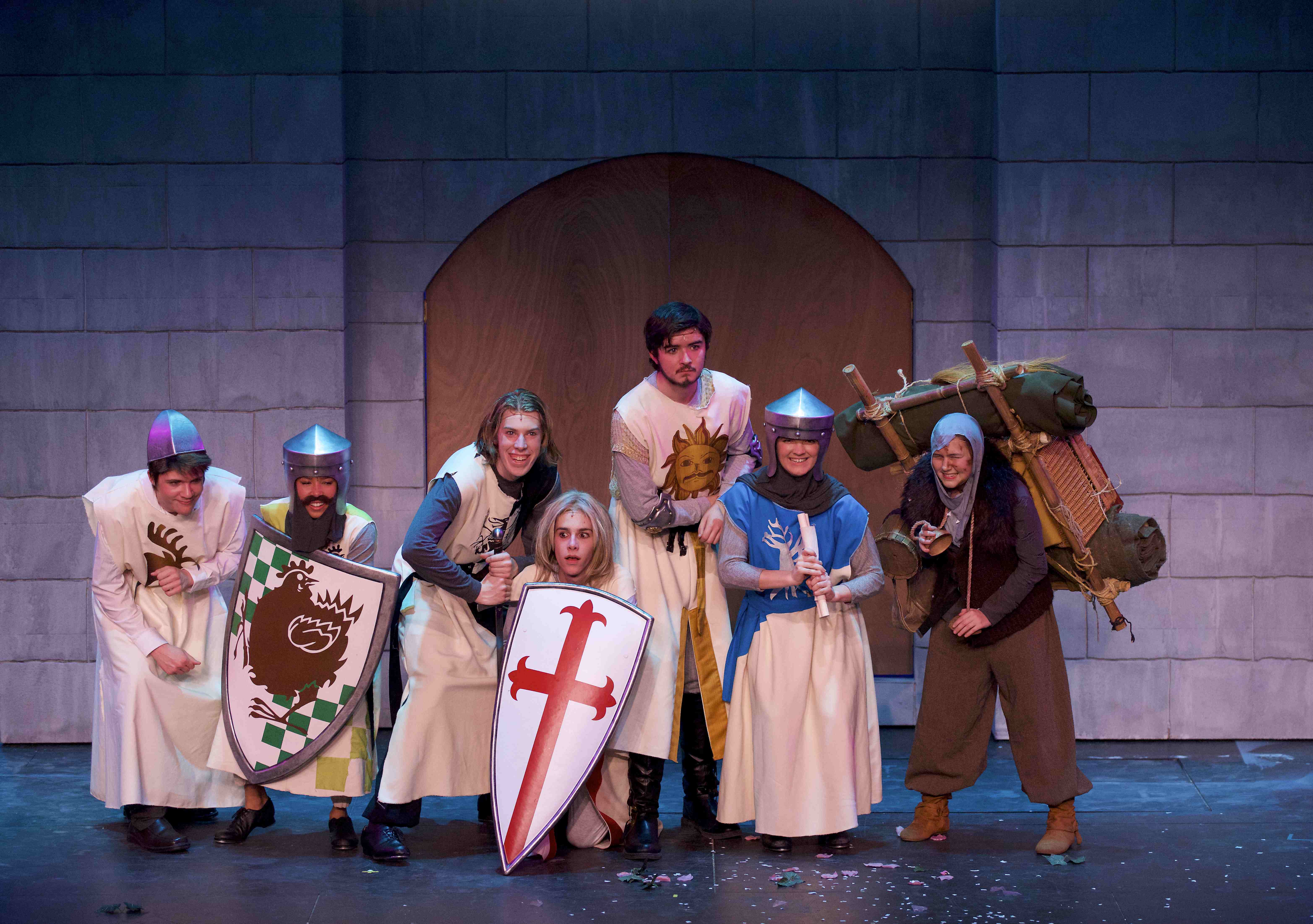 A group of actors are costumed in medieval garb, smiling for a group photo.