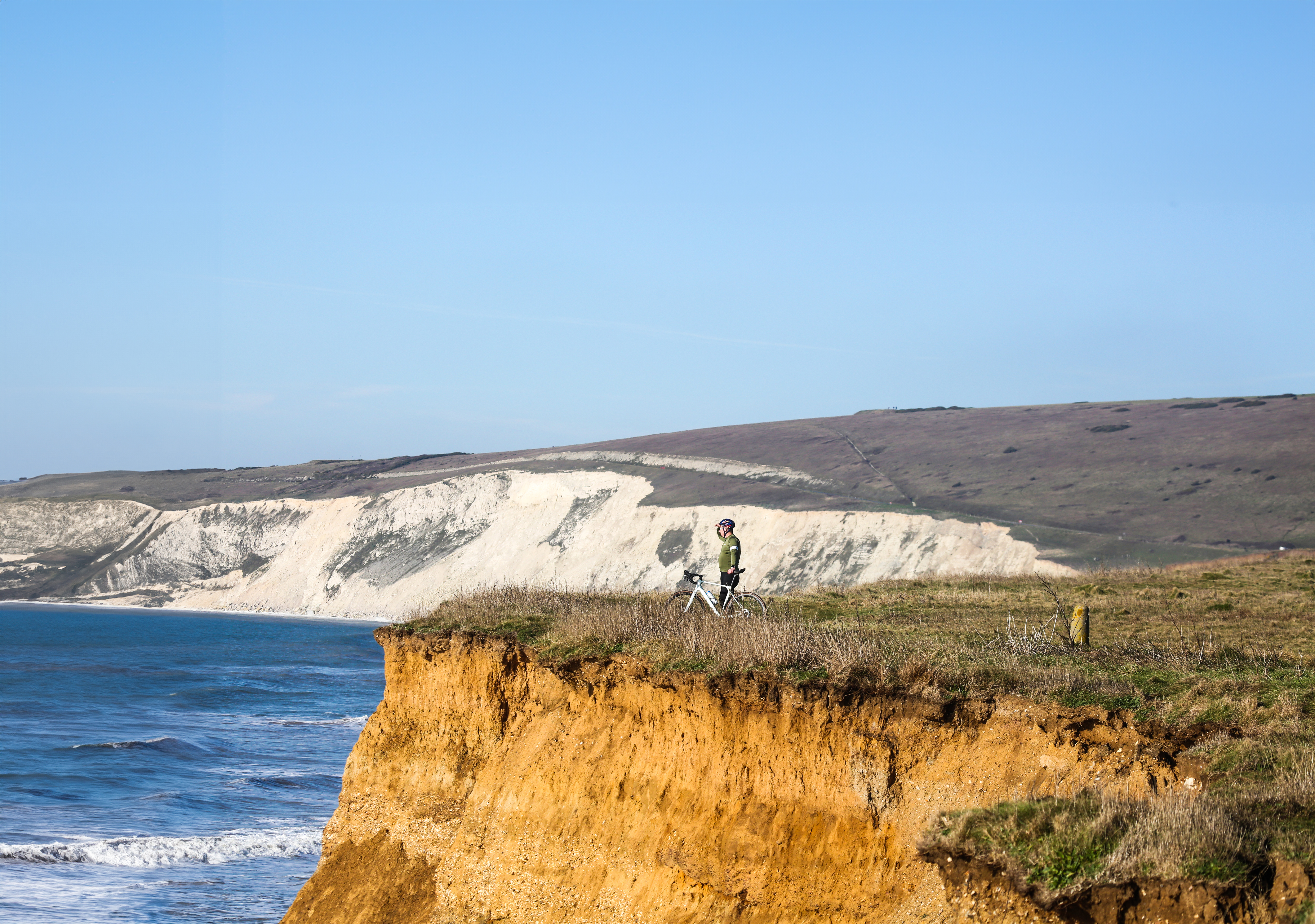 Man looks over cliff with bike