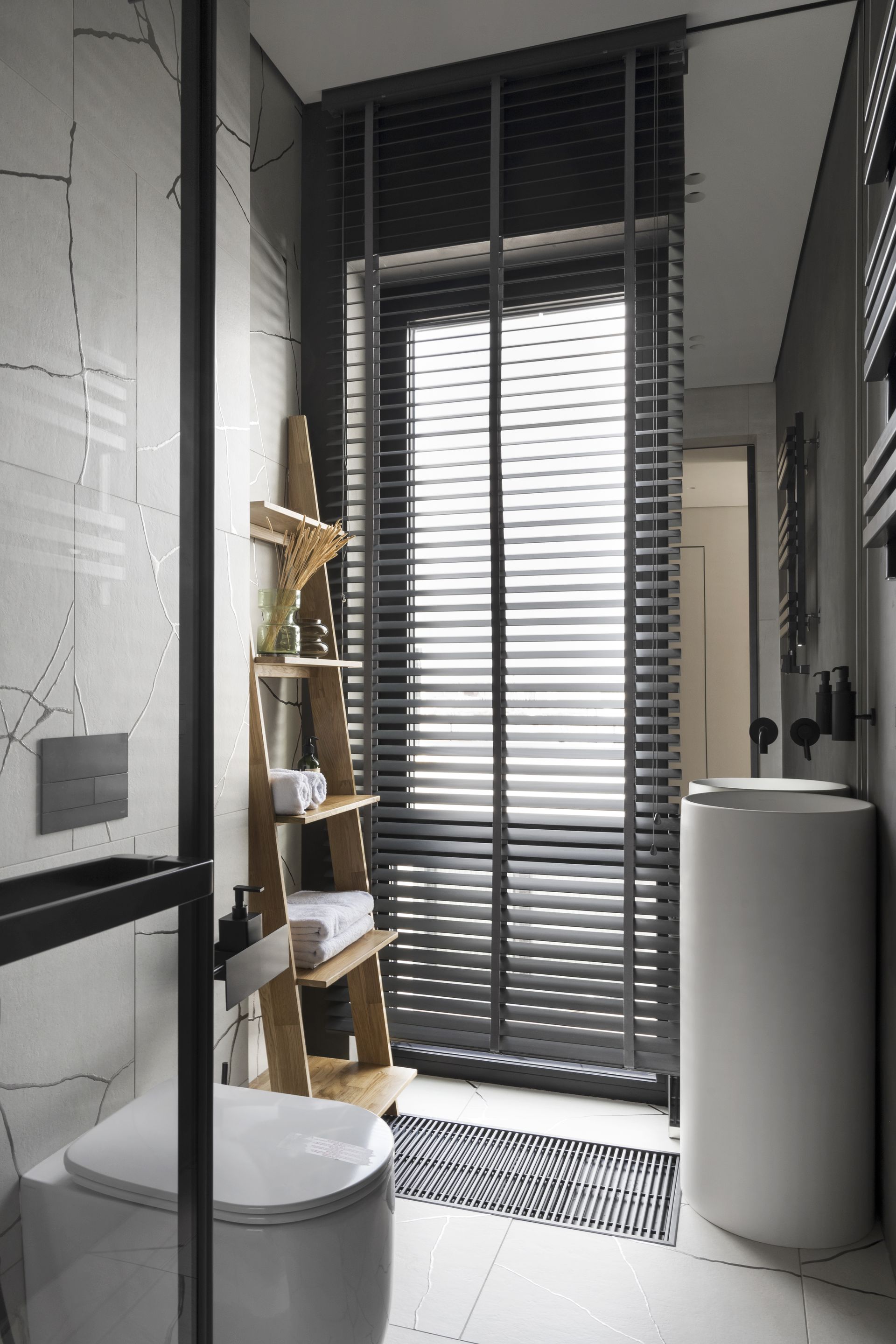 Ένα μπάνιο σε λευκό χρώμα, με ξύλινη σχάρα που χωράει πετσέτες και άλλα αξεσουάρ