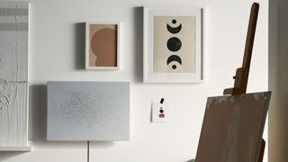 the ikea symfonisk picture fram speaker hung up on a wall with other pieces of art