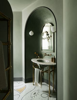 green bathroom with vintage vanity unit and brass taps