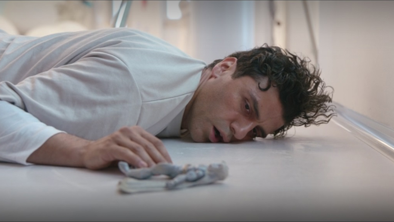 Marc Spector lies on the floor of a psychiatric hospital with a Moon Knight action figure in the Disney Plus show