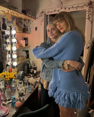 Taylor Swift hugging Cara Delevingne in a blue sweater at a performance of Cabaret