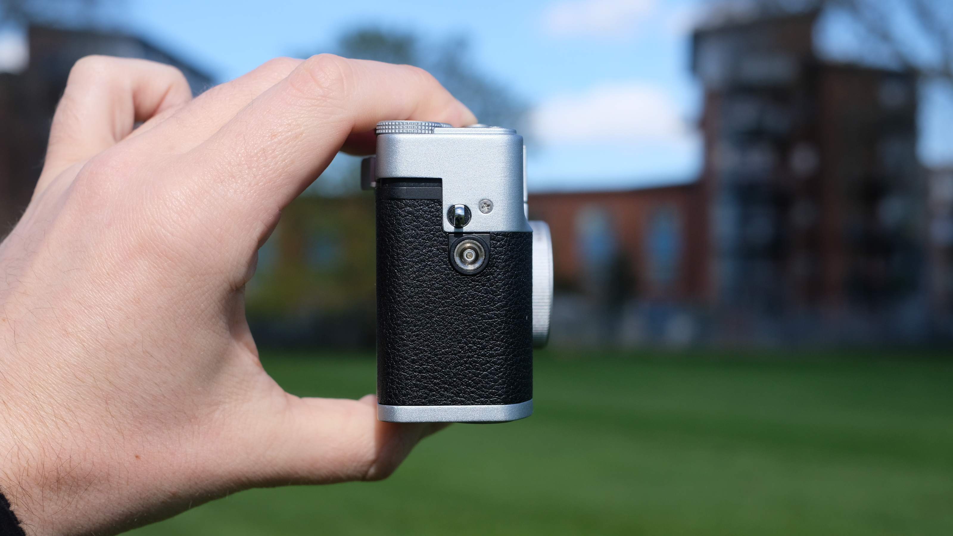 Photograph of man's hand holding the Lomography Lomo MC-A analog compact camera, showing side-on view