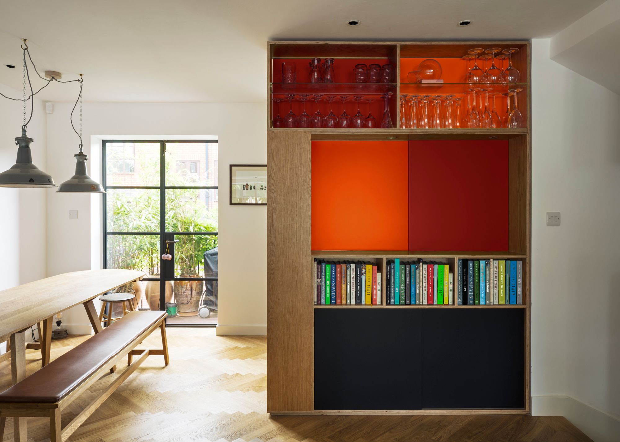 A ktichen in wood, with wooden floor, and a red sliding door