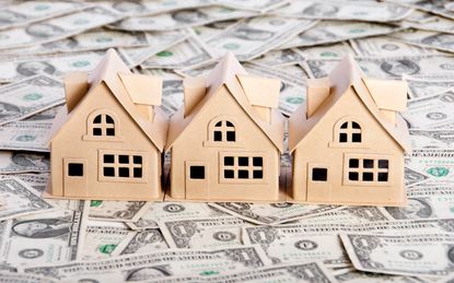 picture of small model housing on a table covered with money