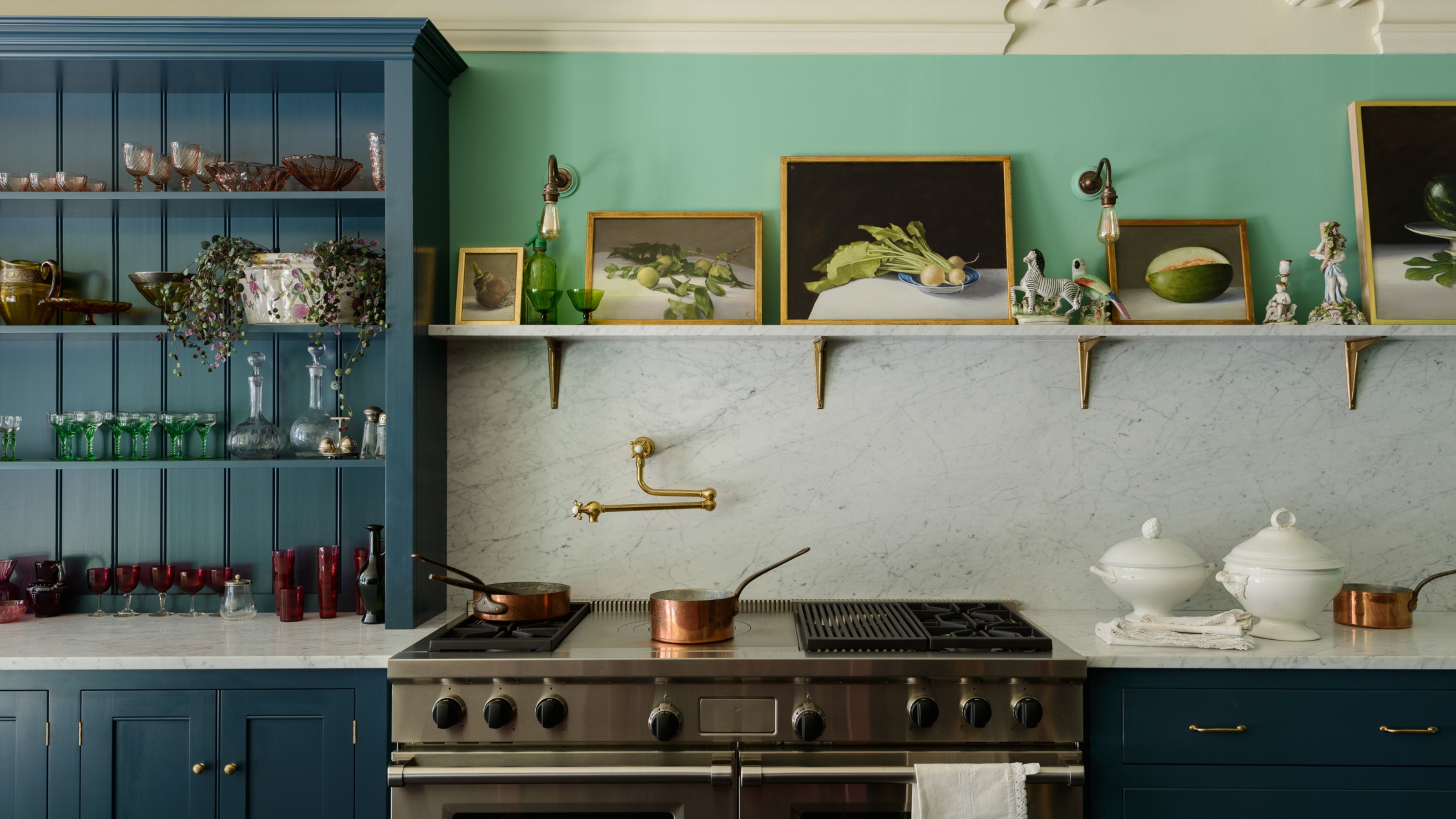 A kitchen with green walls, a marble countersplash, and a navy blue hutch decorated with kitchenware and decor