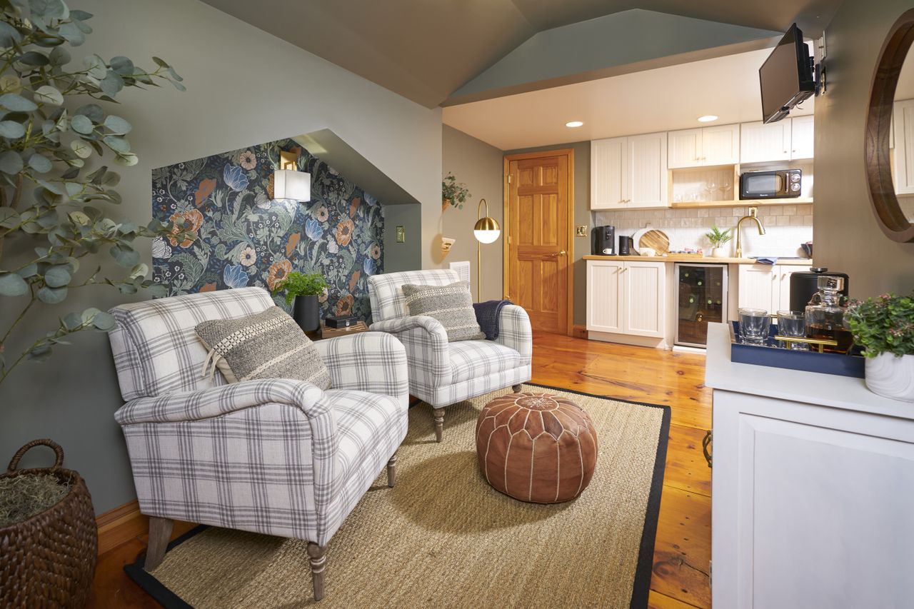 A morning kitchen with wooden flooring, two armchairs and white cabinetry