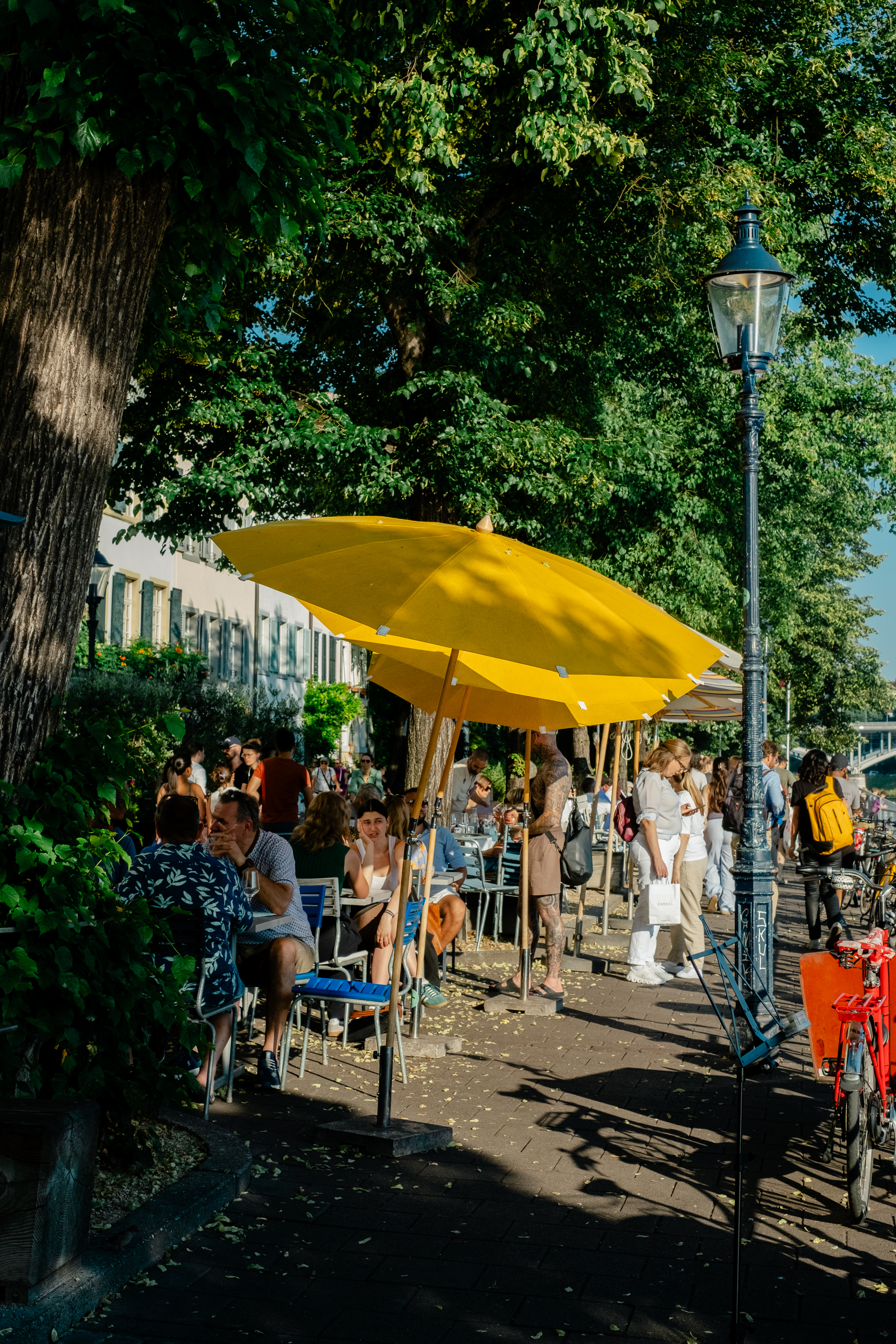 People are photographed out in the sunshine in a Swiss town characterized by beautiful architecture, lush greenery, and art installations.