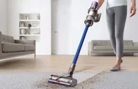 The Dyson V11 Torque Drive vacuuming the living room moving from hard floor to a rug