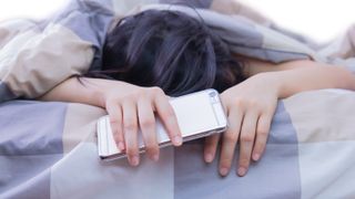 Woman in bed face down holding iPhone