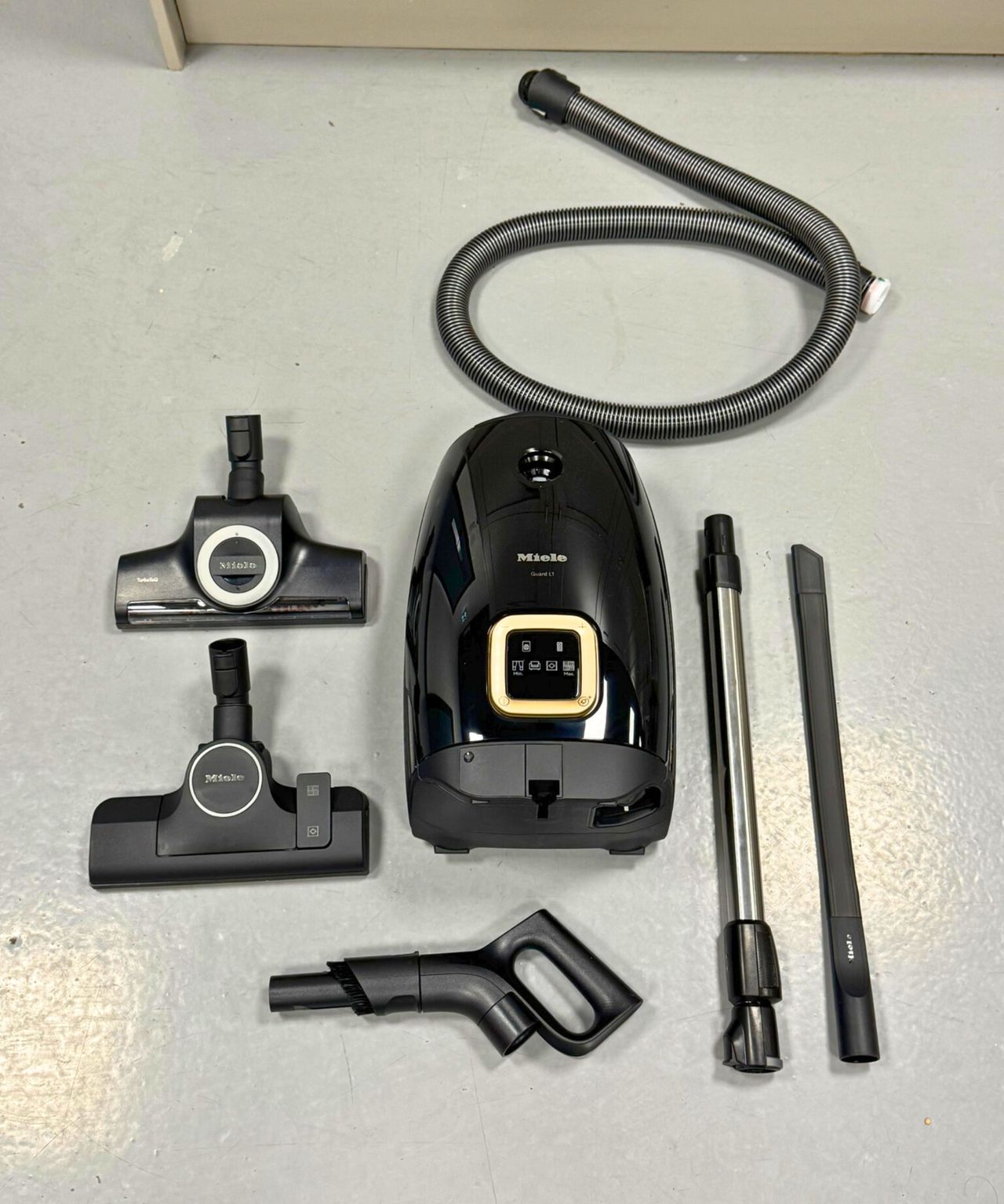 All parts and attachments of the Miele Guard L1 Cat and Dog canister vacuum on gray floor in Future test center.
