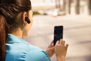 A woman uses a bluetooth ear bud