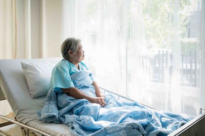 Shadowy photo of older woman sitting up in a hospital bed