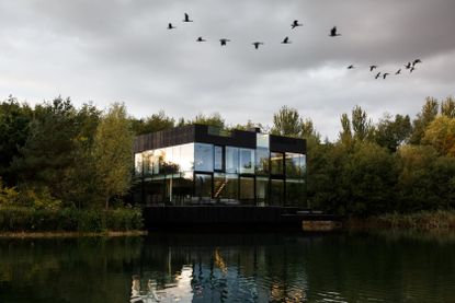 A two-floor, all-glass villa, on the lake, surrounded by woods.