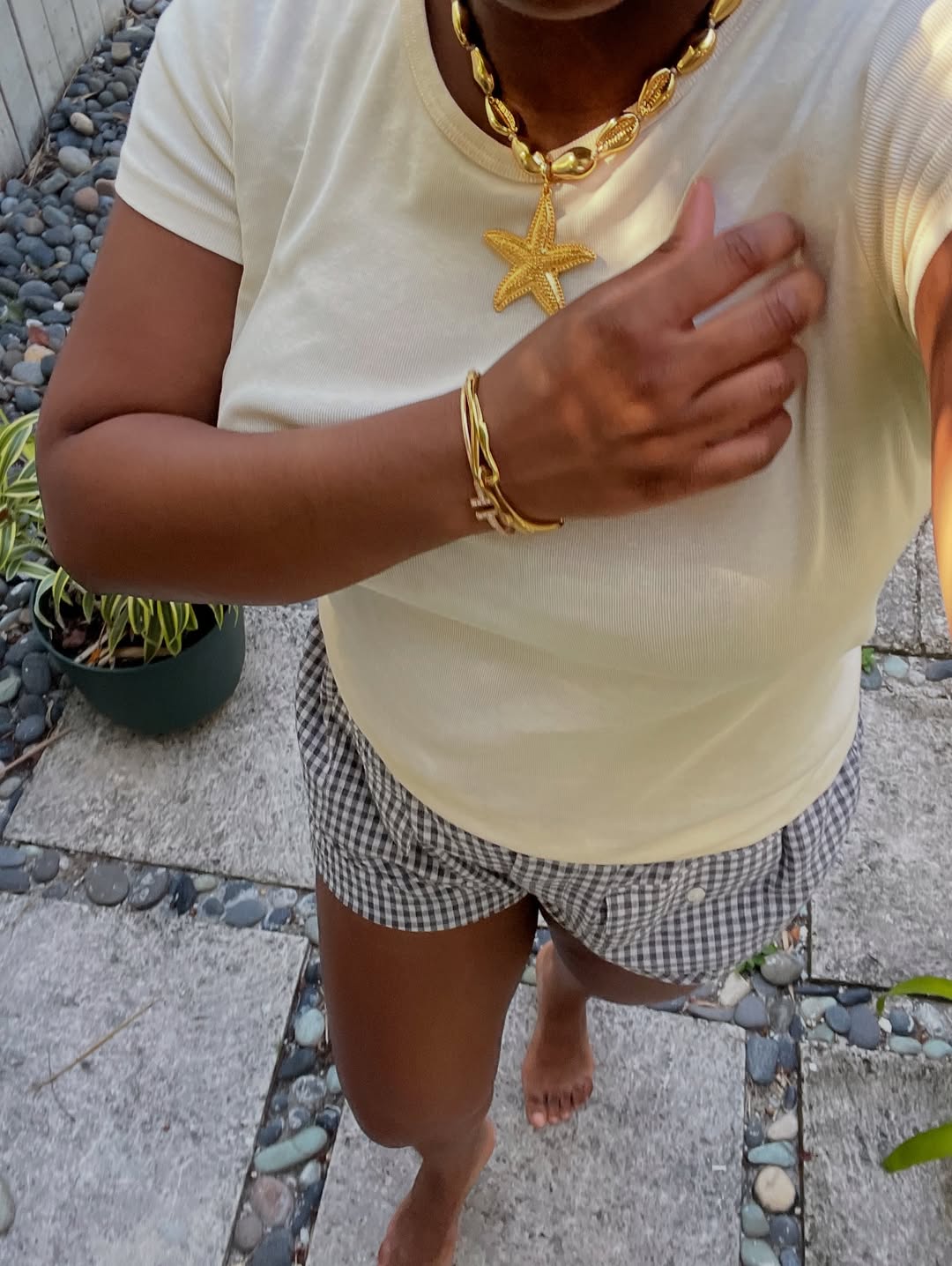 Candice wearing a starfish necklace, yellow top, and gingham shorts