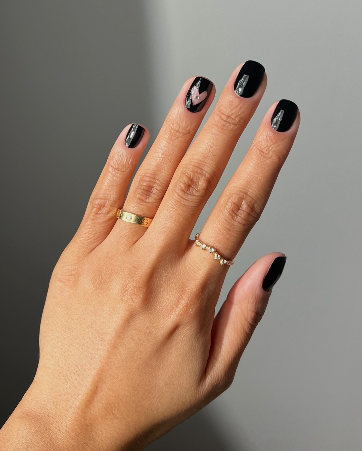 A glossy, negative space black heart manicure by Iram Shelton