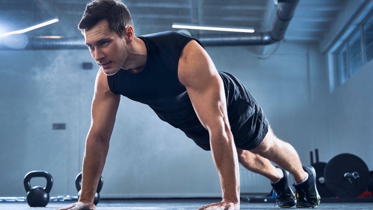Man performing a wide push-up in the gym during bodyweight workout