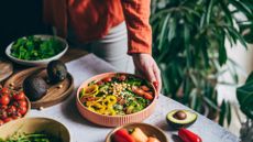 Bowl of high protein and high fibre foods on table with woman's hand reaching out towards it