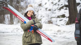 A child hugs her skis
