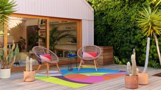 Ruggable x Monica Ahanonu collection outdoor rug on terrace of house with chairs and pillows
