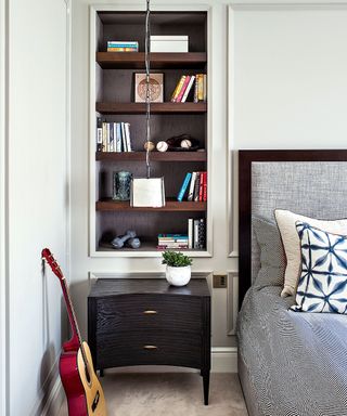 bedroom with bookshelves, bedside table and guitar