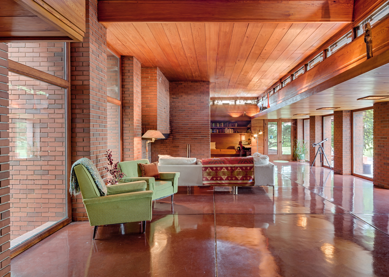 a wooden mid century room with large windows and a panelled ceiling