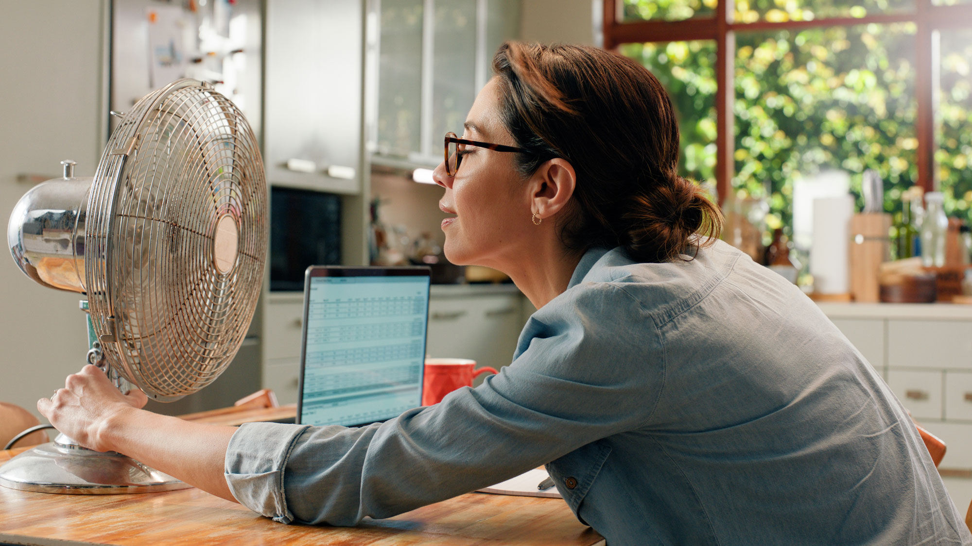 woman in front of fan with laptop on table