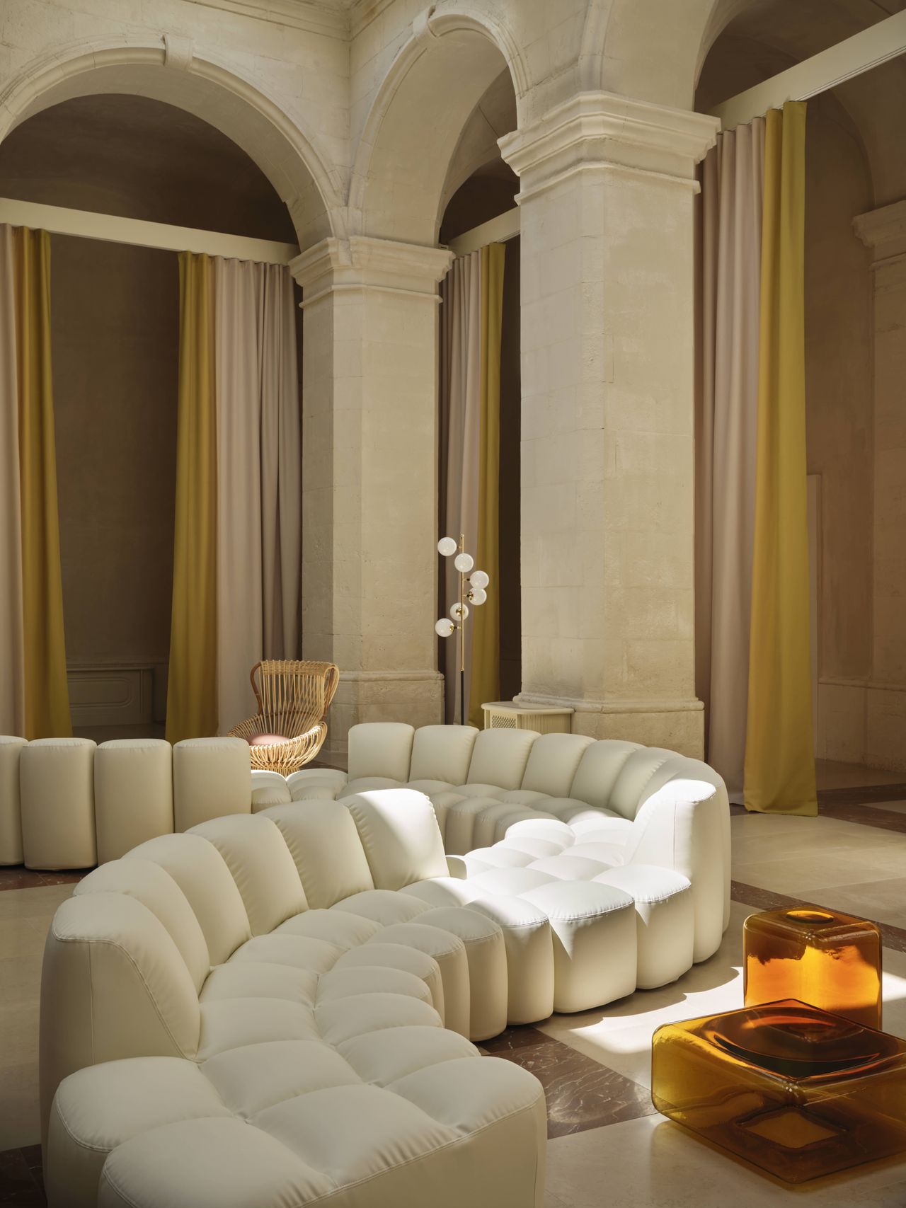 A former convent now converted into a hotel boasts buttery surfaces brought to life by fanciful decor like winding modular sofas in pale white, glass sculptures, and standing lamps.