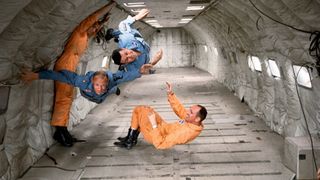 Three astronauts floating in zero gravity