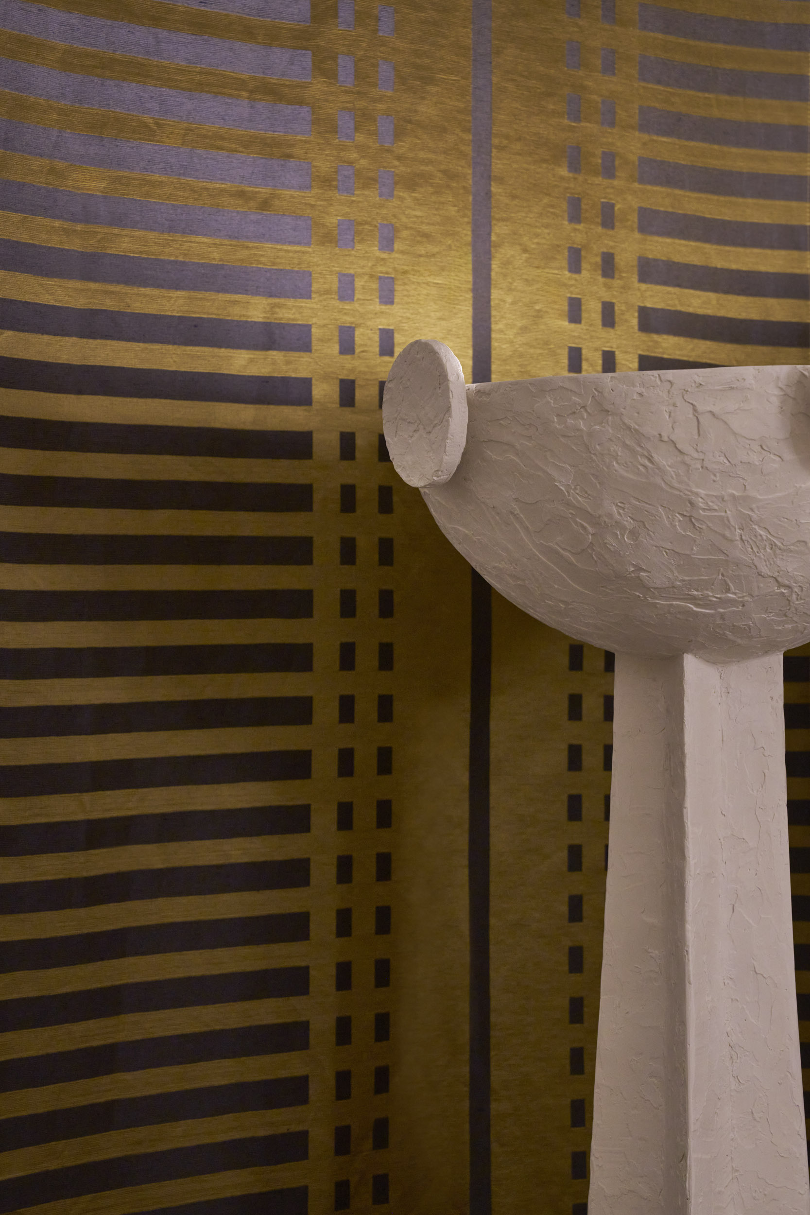 A series of interior shots of beautifully furnished spaces with a blue, white, and gold palette and plenty of textural elements like artworks, handcrafted accessories, and pendant lighting.