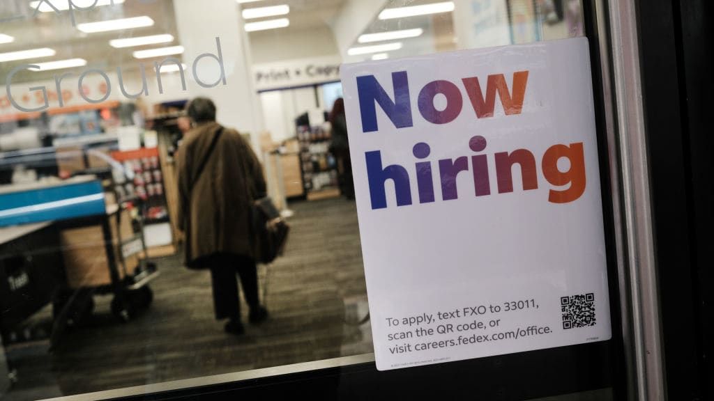 A &amp;quot;now hiring&amp;quot; sign on a store&amp;#039;s door.