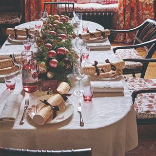 A dining room with a the table set for a Christmas dinner with folded napkins with the ends tucked under next to the plates