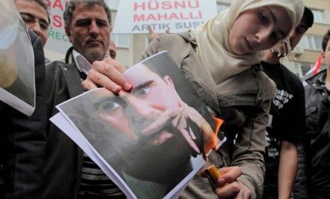 A protester burns a picture of Syrian President Bashar al-Assad May 13, 2011: Al-Assad issued a pardon for crimes committed during the protests but public anger has only risen.