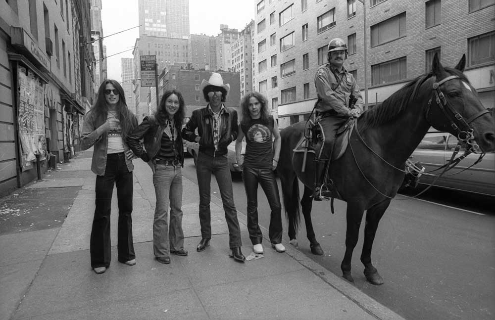 Thin Lizzy pose in a New York street next to a policeman on a horse