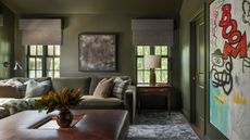 Media room with olive green painted walls and painted door, leather ottoman, green velvet sofa and modern art