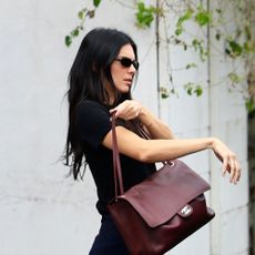 Kendall Jenner wearing a black T-shirt, relaxed-fit white jeans, burgundy ballet flats, and a burgundy Chanel Maxi Flapbag in Los Angeles