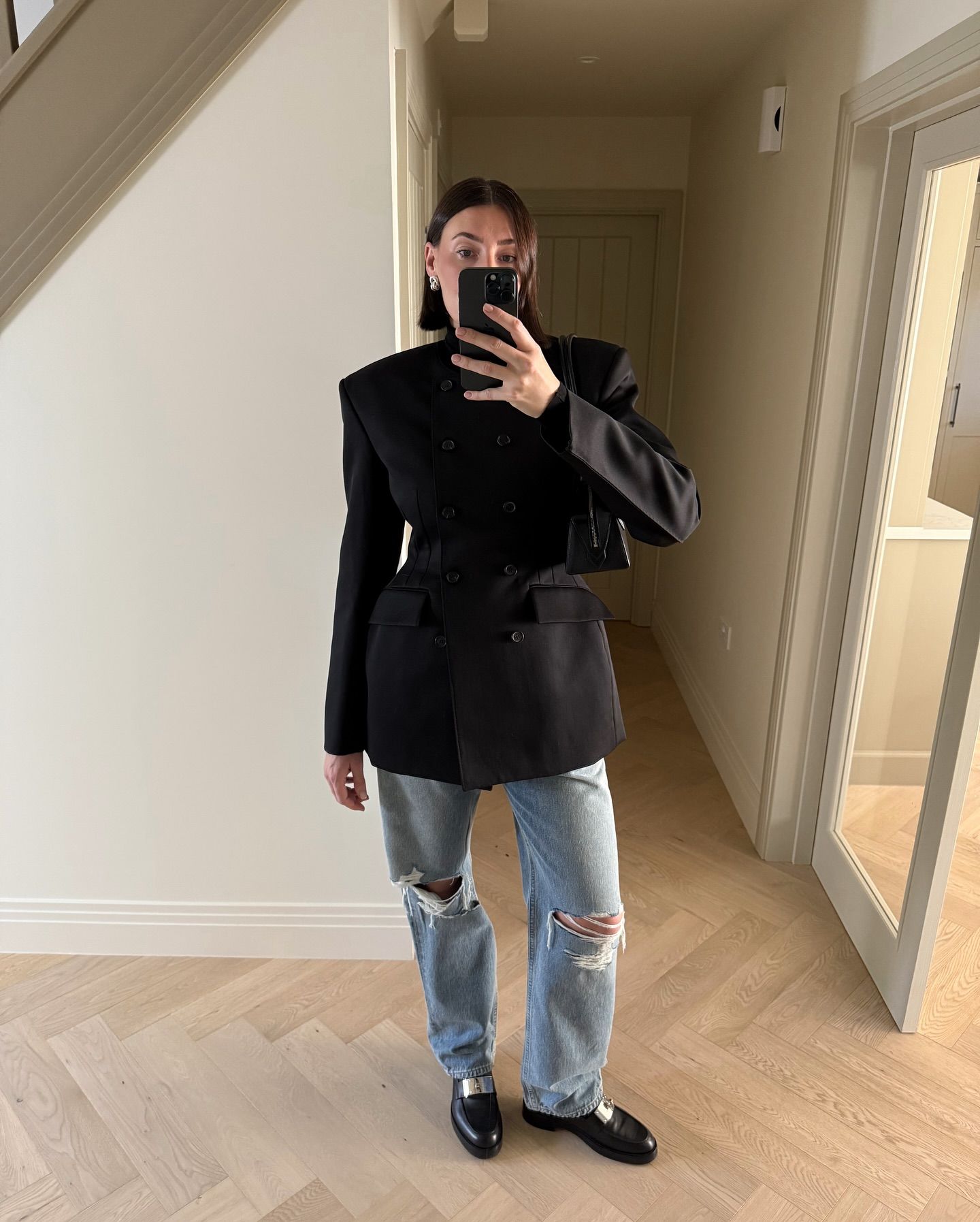 Woman wears waisted blazer, blue jeans and black loafers